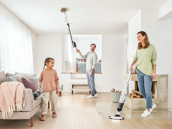 Eine Familie putzt gemeinsam verschiedene Bereiche der Wohnung mit einem Bosch Flexxo Akku-Staubsauger.