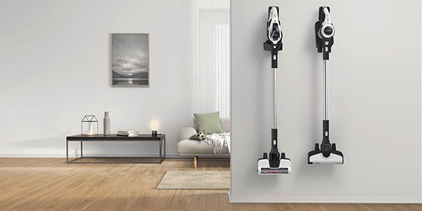 Two cordless vacuums hang on the wall in their charging stations.