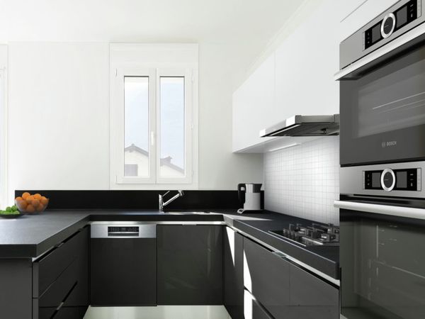 Moderna cocina abierta negra en forma de U con un mostrador que se dobla como una pequeña área para sentarse