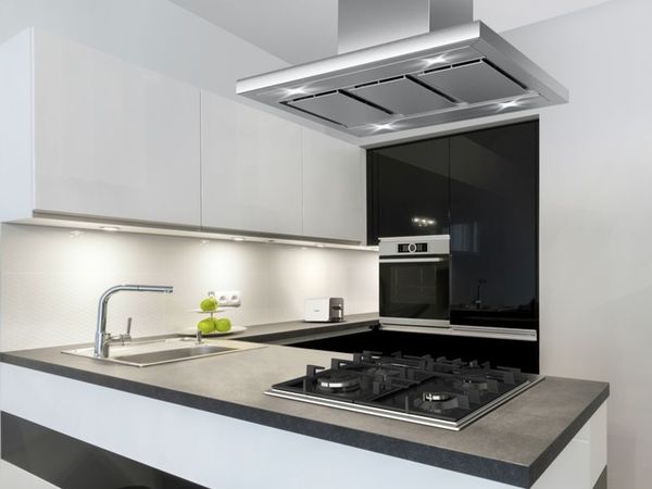 Малка, модерна черно-бяла кухня с вградени уреди за готвене и бели съдове върху отворени рафтове