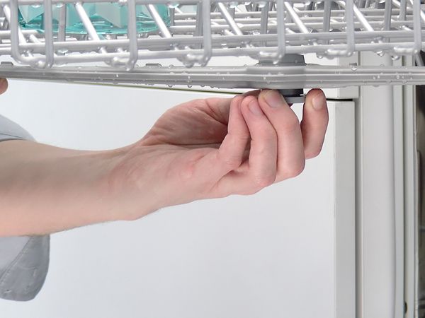 Person clipping a dishwasher spray arm into place.