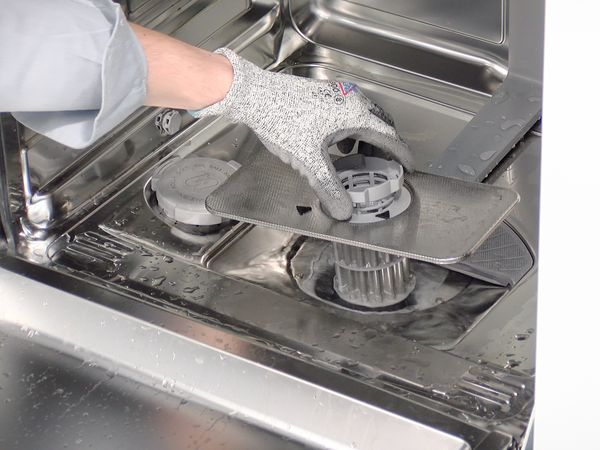 Een hand waarmee de filtereenheid uit een Bosch-vaatwasser wordt verwijderd