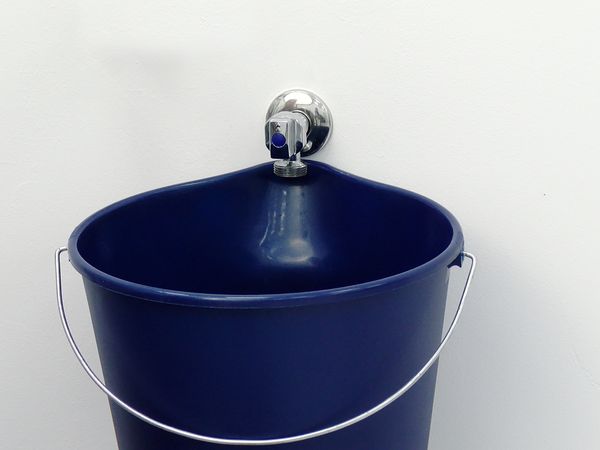 Seau bleu sous un robinet d’eau, eau qui coule à faible pression