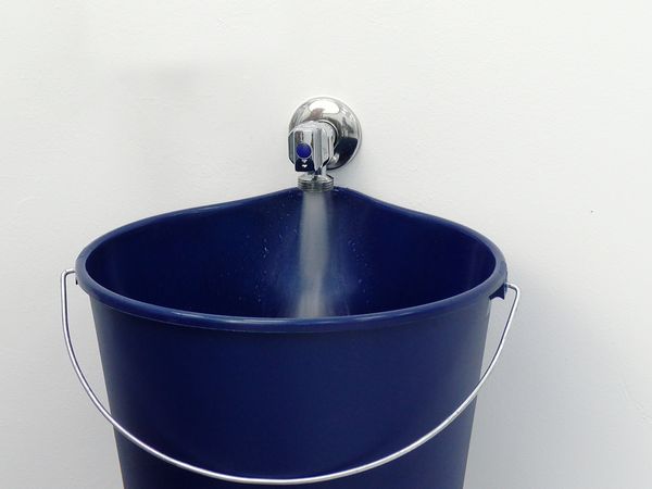 Seau bleu sous un robinet d’eau avec de l’eau qui coule