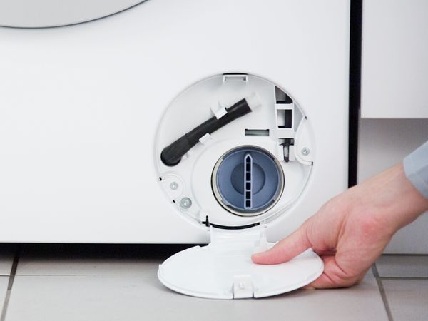 En person åpner og fjerner serviceluken til en Bosch oppvaskmaskin
