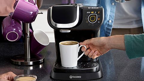 Tassimo machine and coffee cup in a hand