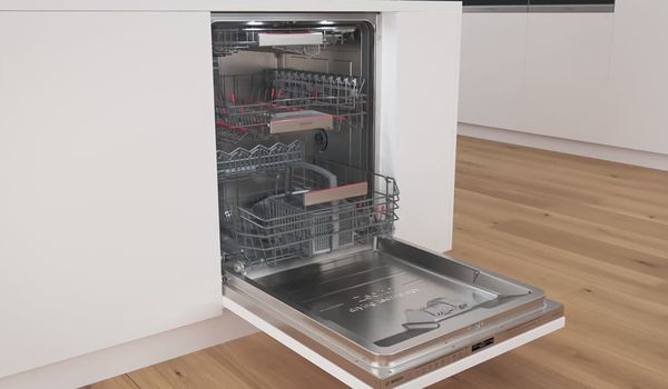 Nyitott Bosch beépíthető mosogatógép egy fehér konyhában.