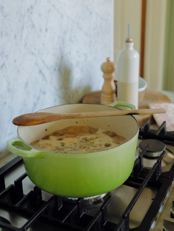 Vegetable soup on the stove with wooden spoon