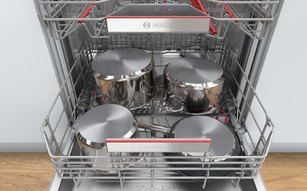Porte de lave-vaisselle avec bandeau de commande à l’avant montrant un panier supérieur avec de grands ustensiles comme des soucoupes et un verre à vin