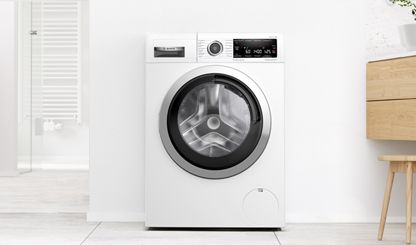 Mașină de spălat Bosch independentă într-o baie albă modernă
