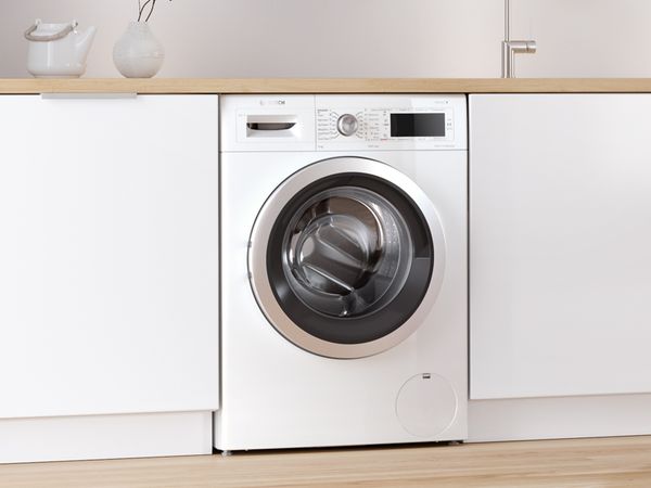Boschin työtason alle sijoitettu edestä täytettävä pyykinpesukone nykyaikaisessa valkoisessa keittiössä