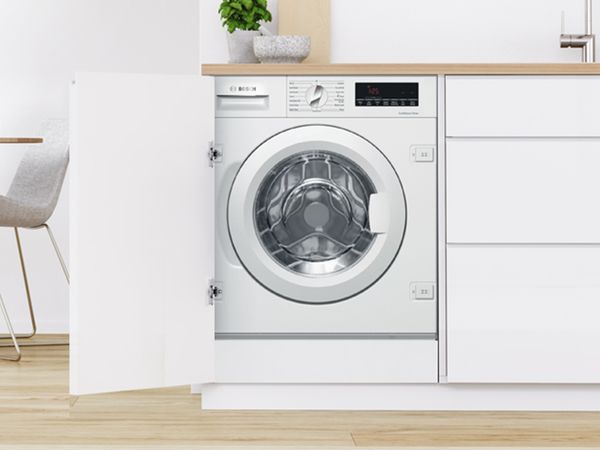 Bosch built-in front load washer in a modern white kitchen