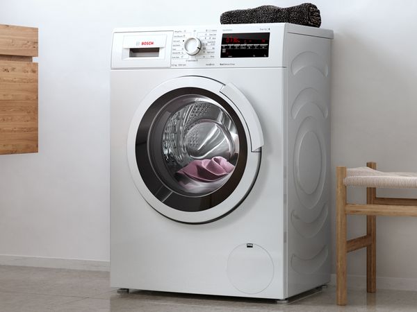 Mașină de spălat rufe Bosch SlimLine cu încărcare frontală într-o baie albă modernă