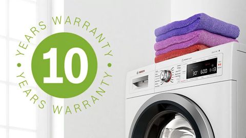 Zusammengelegte Kleidung auf einer freistehenden Bosch Waschmaschine und der Aufkleber für die 10-Jahres-Garantie 