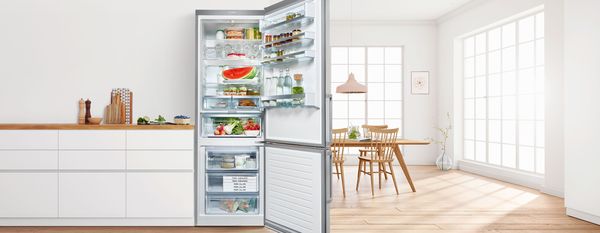 Moderna telpa ar atvērtu Bosch ledusskapi-saldētavu, kurā redzami dažādi uzglabāti pārtikas produkti 
