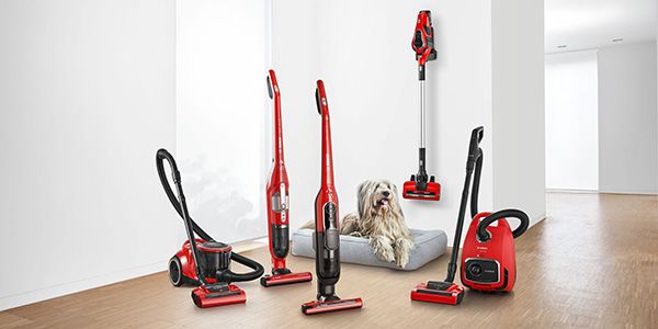 Lineup of five Bosch ProAnimal vacuum cleaners next to shaggy dog laying on its bed