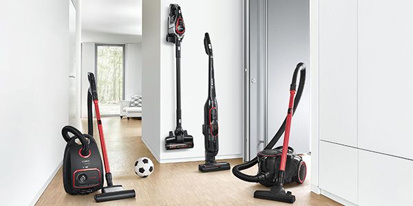 Lineup of four Bosch ProPower high-suction vacuums, bagged, Unlimited, Athlet and bagless, next to football 