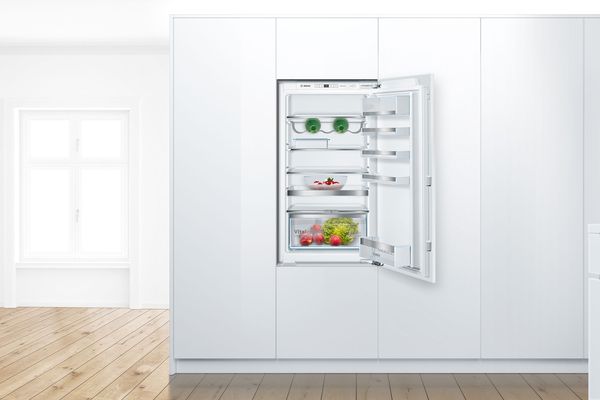 Een koelkast met openstaande deur staat in de keuken.