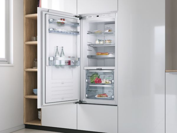 Built-in Bosch fridge with open door showing fresh food and drinks inside.