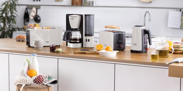 Zestaw ComfortLine w kolorze białym obejmujący toster, ekspres przelewowy do kawy i czajnik. Wiele składników śniadaniowych znajduje się na stole.