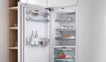 Iebūvējams Bosch ledusskapis ar atvērtām durvīm atklāj svaigus pārtikas produktus un dzērienus tā iekšpusē.