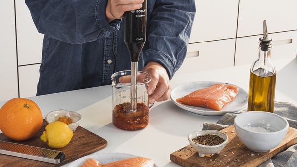 Una persona prepara un adobo para salmón, utilizando una batidora de mano.