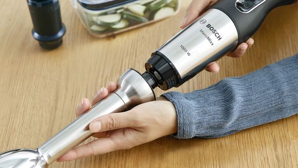 A stainless steel blending shaft being attached to a stainless steel hand blender from Bosch.