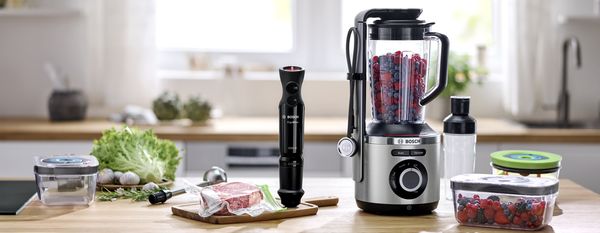 Bosch blender med Fresh Vacuum System på en köksbänk bredvid produkter och tillbehör för vakuumförslutning.