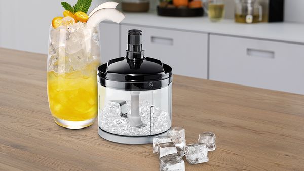 Universalzerkleinerer mit Ice-Crush-Klinge zerkleinert Eis neben einem gekühlten Getränk und Eiswürfeln.
