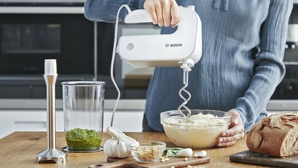 Woman kneading pizza dough with an ErgoMixx hand blender.