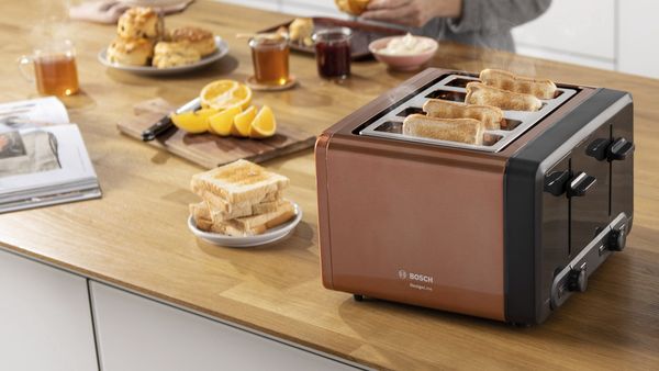 Bread in toaster on breakfast bar surrounding by other brunch food and drink items