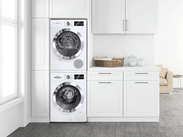 Kleine stapelbare Kombination aus Waschmaschine und Trockner, integriert in eine kleine weisse Landhausküche.