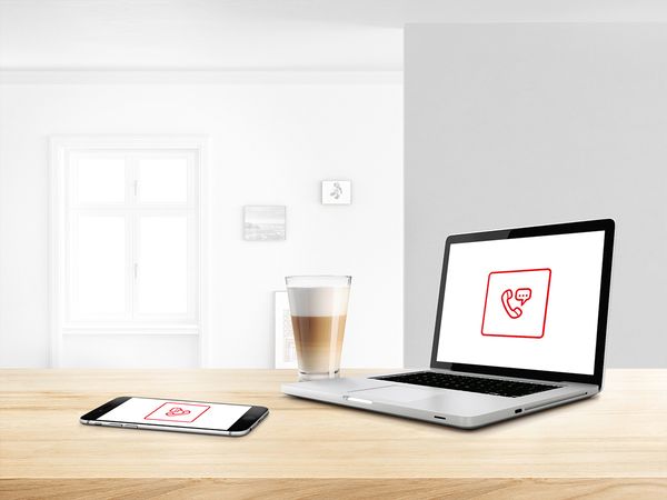 Laptop mit Anrufsymbol auf dem Bildschirm neben einem frischen, grossen Latte.