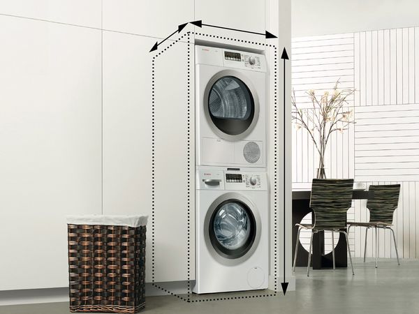 Stacked washing machine and dryer integrated in a flush white wall in a modern kitchen.