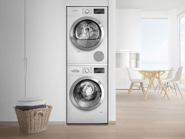 Compact stacked washer and dryer in a bright open kitchen.