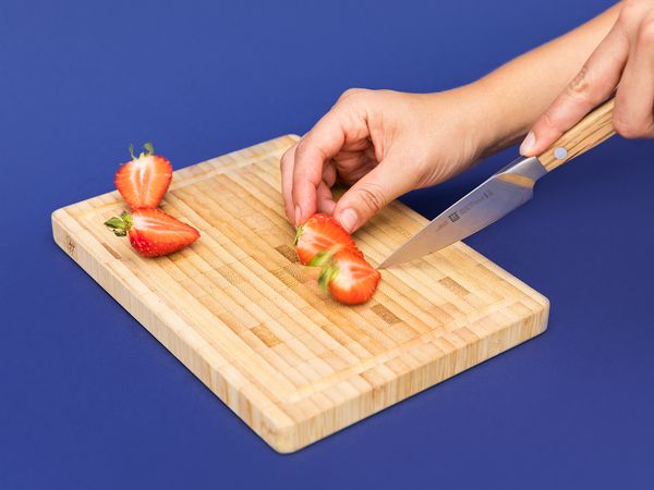 Halving strawberries on a cutting board