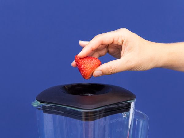 Placing strawberries into a blender