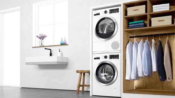Gestapelte Kombination aus Waschmaschine und Trockner, in ein Schrankelement integriert, daneben ein Kleiderschrank.
