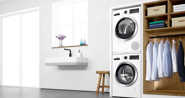 Gestapelte Kombination aus Waschmaschine und Trockner, in ein Schrankelement integriert, daneben ein Kleiderschrank.
