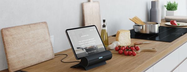 An activated tablet placed in a Smart Kitchen Dock is standing on a worktop.