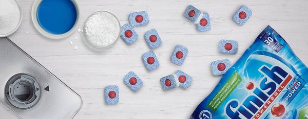 Dishwasher tablets and other types of detergent on a white surface.