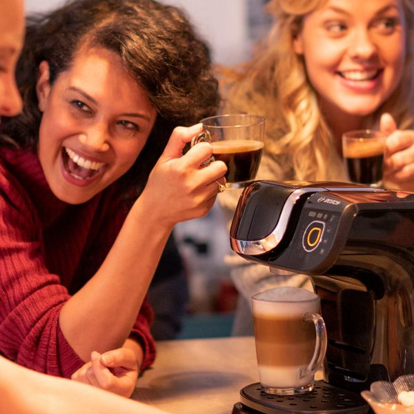 People drinking coffee together surrounding a Tassimo
