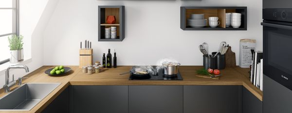 Compacte en moderne U-vormige keuken met een elegant houten werkblad, een geïntegreerde kookplaat en ingebouwde ovens onder elkaar, met uitzicht op een groene tuin.