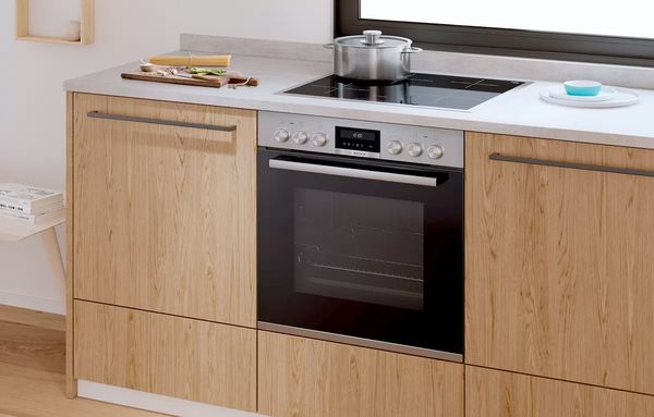 Bosch beépíthető sütő főzőlapvezérléssel egy fa konyhában. 