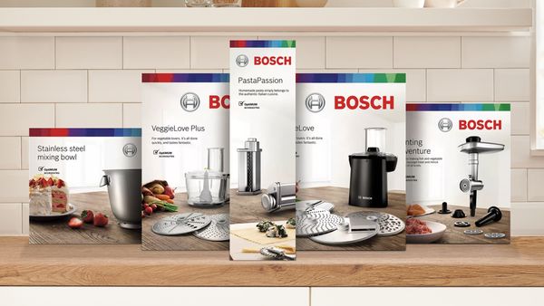 A lineup of different MUM stand mixer attachments in their boxes.