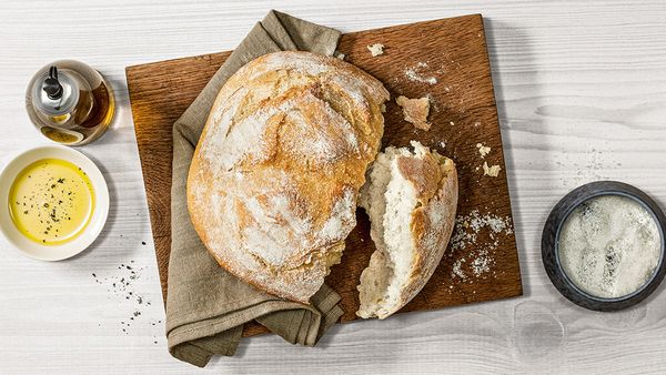 Świeżo upieczony chrupki biały chleb na drewnianej desce do krojenia.