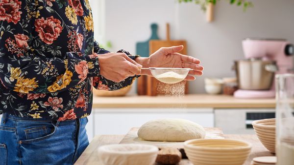 Przesiewanie mąki w celu przygotowania domowej roboty chleba na zakwasie.