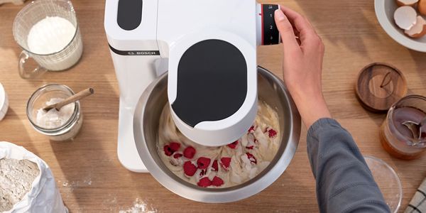A person uses the blender attachment of the stand mixer to make a smoothie.