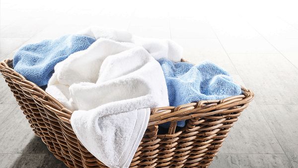 A laundry basket filled to the brim with dirty towels.