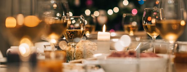 Table with christmas food, candles and wine glasses, lit by candlelight